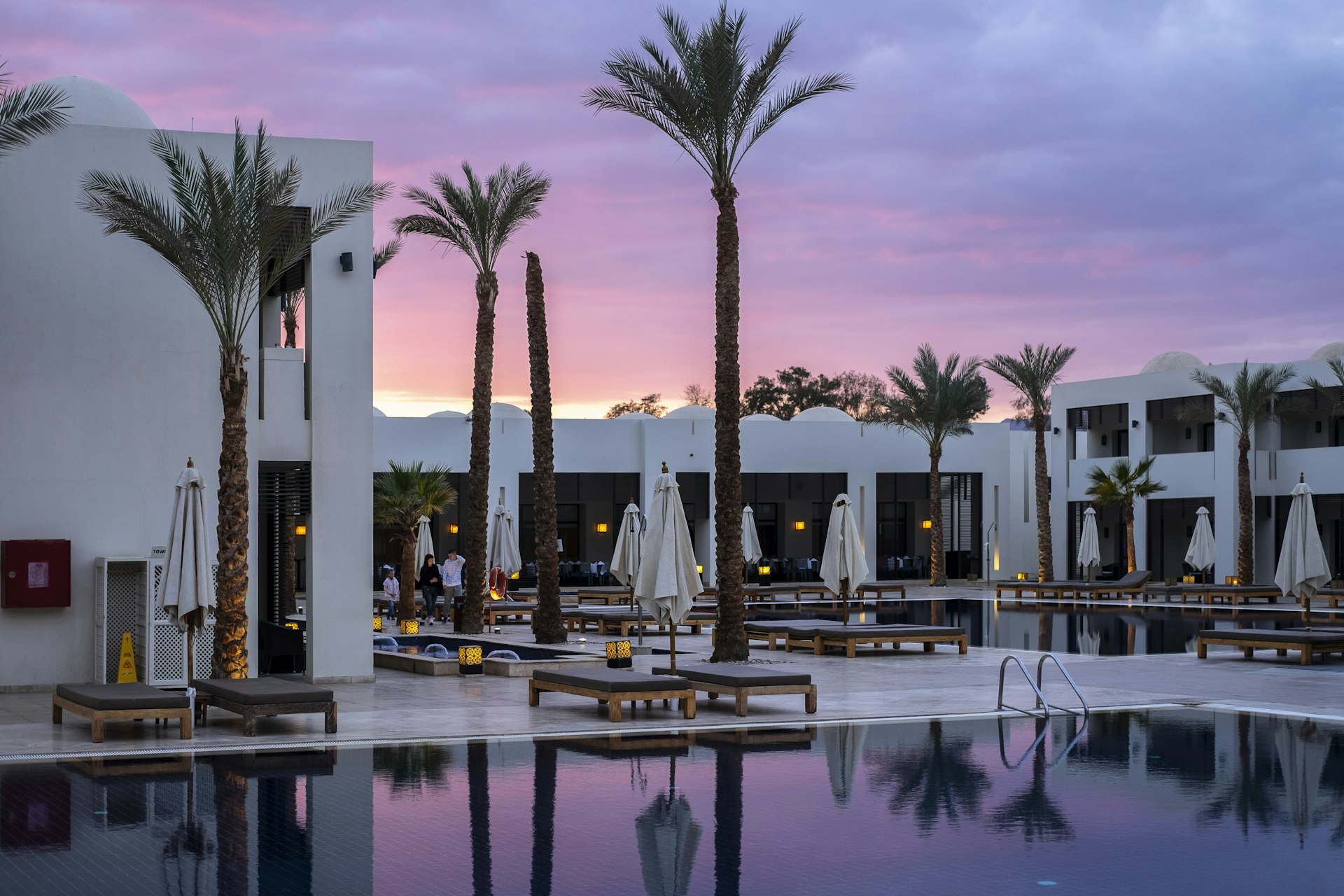 Gün batımında palmiyeli otel havuzu